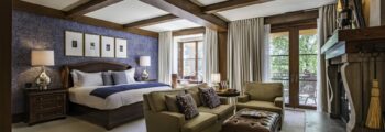 Chambre luxueuse avec cheminée et grande lumière naturelle.